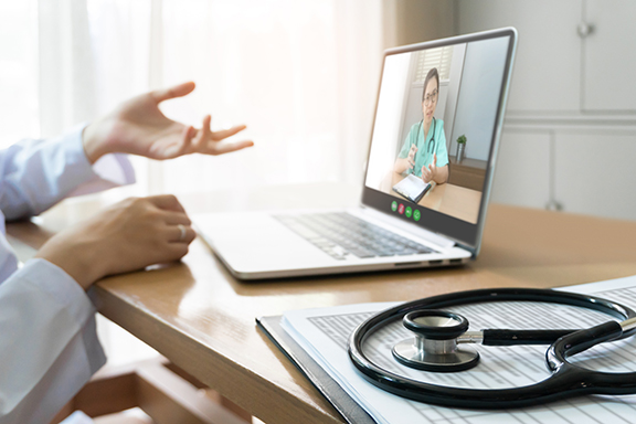 Doctor at desk with laptop during a virtual peer-to-peer consultation