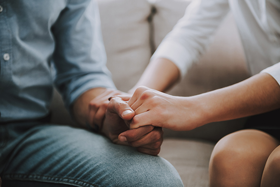 Couple holding hands on sofa